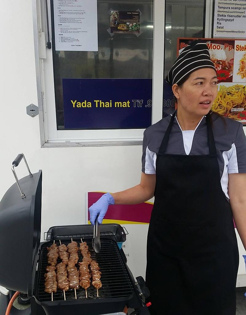 Yada ved grillen foran matvognen, med grillspyd på risten.